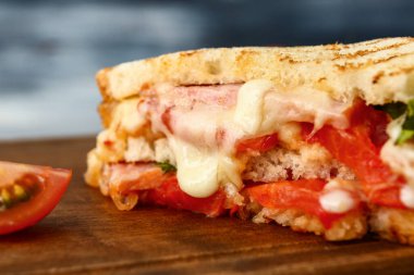 Tasty sandwich with cheese, meat and tomatoes on table, closeup