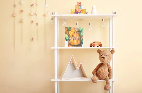 Shelf with baby toys, book and decor near color wall — 스톡 사진