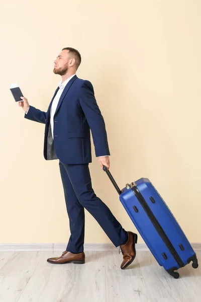 Businessman with passport and luggage near light wall — Stock Photo, Image