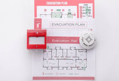 Evacuation plans, smoke detector and manual call point on white background