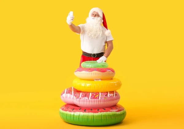 Santa Claus with swimming rings taking selfie on color background. Concept of vacation — Stock Photo, Image