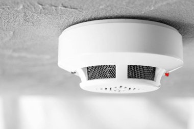 Modern smoke detector on ceiling