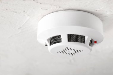Modern smoke detector on ceiling