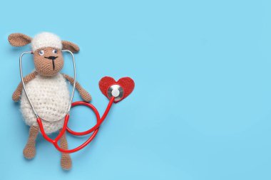 Stethoscope, baby toy and heart on color background