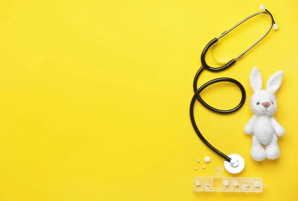 Stethoscoop, pillen en baby speelgoed op kleur achtergrond — Stockfoto