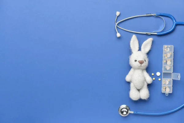 Stethoscoop, pillen en baby speelgoed op kleur achtergrond — Stockfoto