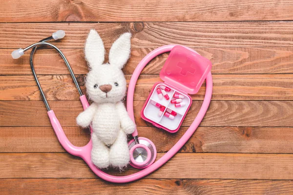 Stethoscope, pills and baby toy on wooden background — Stok fotoğraf