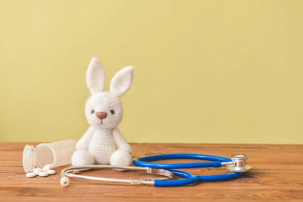 Stethoscope, pills and baby toy on table — Stock Photo, Image