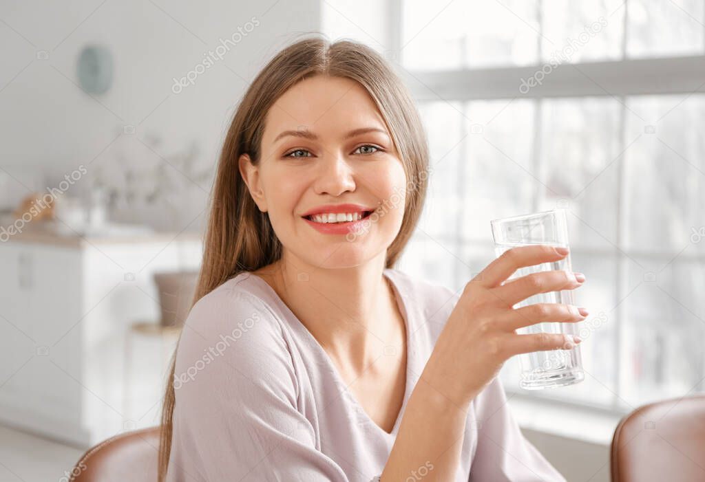 Beautiful young woman drinking water at home