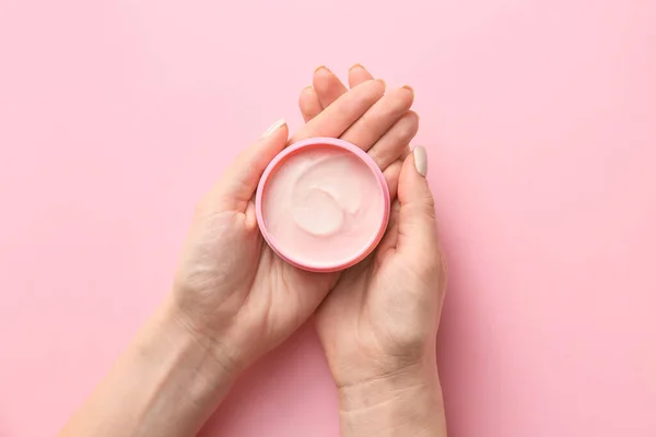 Mains féminines avec pot de crème sur fond de couleur — Photo