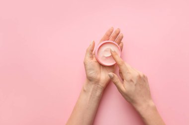 Arkaplanda krema kavanozu olan kadın elleri