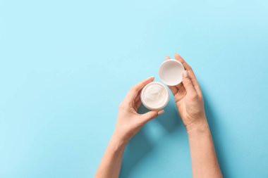 Arkaplanda krema kavanozu olan kadın elleri