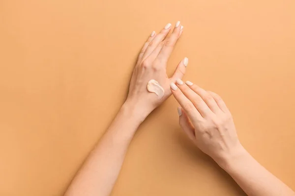 Mulher aplicando creme nas mãos contra fundo de cor — Fotografia de Stock