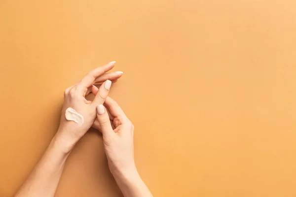 Woman applying cream on hands against color background — Stock Photo, Image