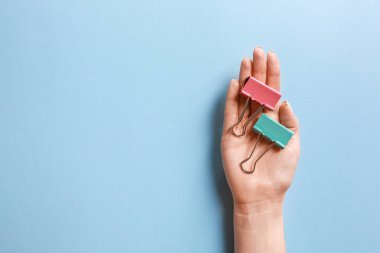 Renk arkaplanı üzerine kağıt için ataç kullanan kadın eli