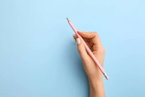 Female hand with pencil on color background — Stock Photo, Image