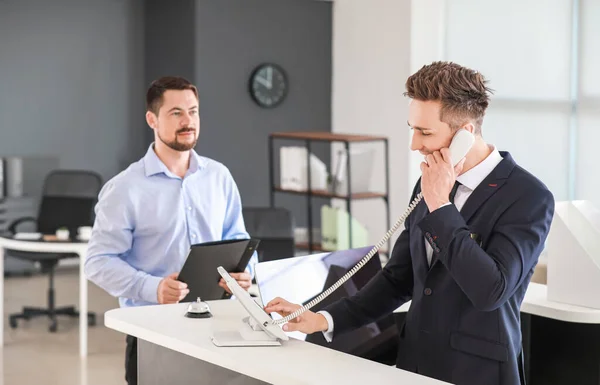 Male receptionist talking on phone in office — Stock Photo, Image
