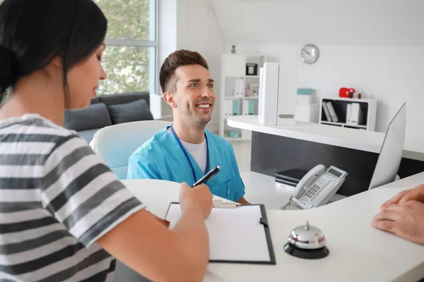 Mannelijke receptioniste werkt met patiënten in de kliniek — Stockfoto