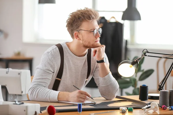 Young tailor working at table in atelier — Stock Photo, Image