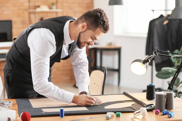 Young tailor working at table in atelier — Stock Photo, Image