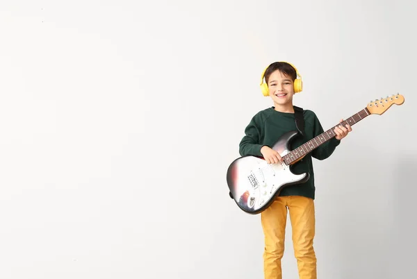 Kleiner Junge spielt Gitarre auf hellem Hintergrund — Stockfoto