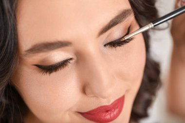 Makyaj sanatçısı genç ve güzel bir kadınla çalışıyor.