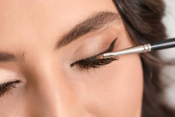 Make-up kunstenaar werken met mooie jonge vrouw, close-up — Stockfoto