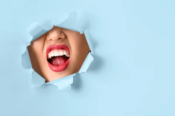 Face of beautiful young woman visible through hole in color paper — Stock Photo, Image