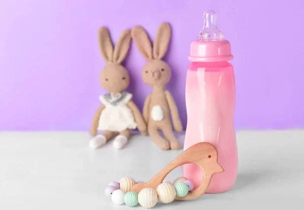 Renkli oyuncakları olan bebek için bir şişe süt. — Stok fotoğraf