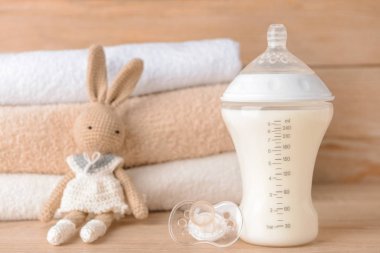 Emziği ve oyuncağı olan bebek için bir şişe süt.