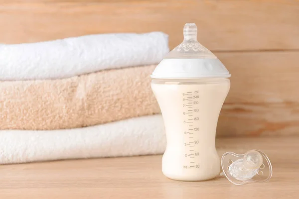 Lahvička mléka pro kojence a dudlík na dřevěném stole — Stock fotografie