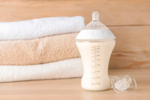 Bottle of milk for baby and pacifier on wooden table — Stock Photo, Image