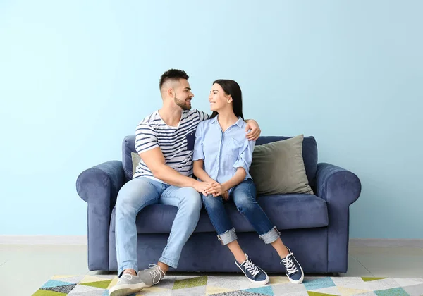 Young couple sitting on sofa at home — Stock Photo, Image