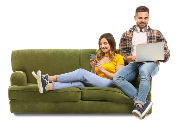 Jeune couple avec ordinateur portable et téléphone portable assis sur le canapé sur fond blanc — Photo