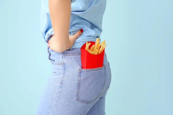 Giovane donna con patatine fritte in tasca su sfondo colore, primo piano — Foto Stock