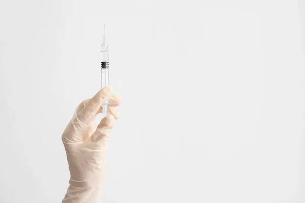 Hand van de cosmetoloog die de spuit met vulmiddel voor injectie op een lichte achtergrond vasthoudt — Stockfoto