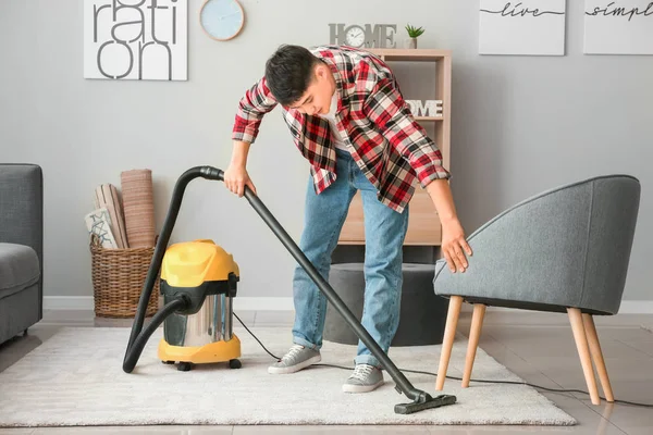 Young Asian man hoovering floor at home — Stock Photo, Image