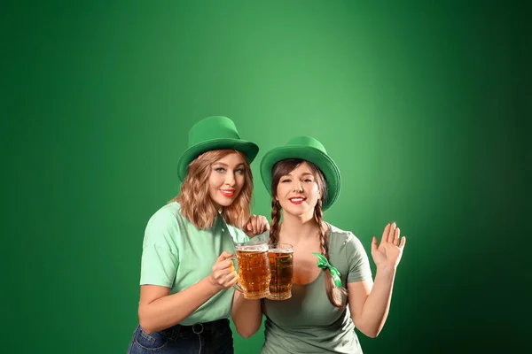 Grappige jonge vrouwen met bier op gekleurde achtergrond. St. Patrick 's Day viering — Stockfoto