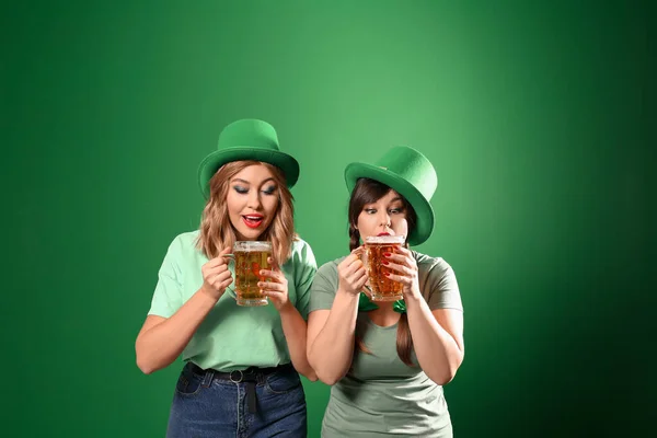Funny young women with beer on color background. St. Patrick\'s Day celebration