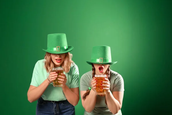 Grappige jonge vrouwen met bier op gekleurde achtergrond. St. Patrick 's Day viering — Stockfoto