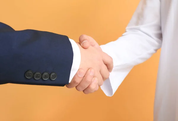 Arab man and his business partner shaking hands on color background — Stock Photo, Image