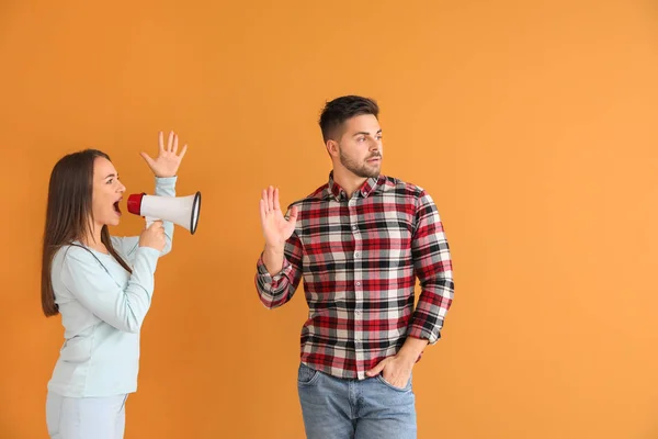 Arg kvinna med megafon skriker på sin man på färg bakgrund — Stockfoto