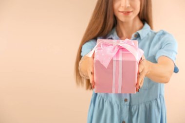 Beautiful young woman with gift on color background. International Women's Day celebration