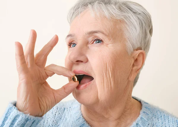 Senior woman with fish oil on white background — Stock Photo, Image