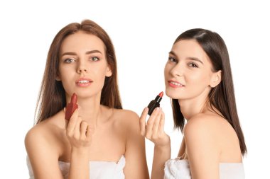 Beautiful young women applying makeup on white background