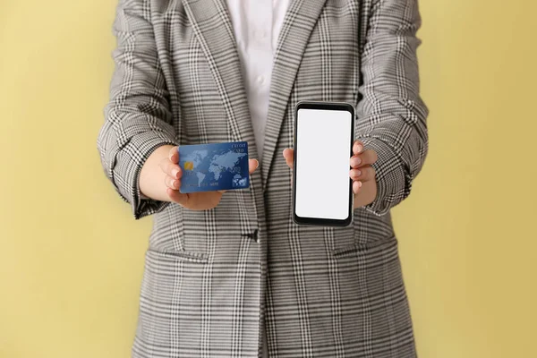 Frau mit Kreditkarte und Handy auf farbigem Hintergrund, Nahaufnahme. Konzept des Online-Banking — Stockfoto