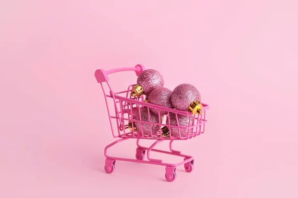 Warenkorb mit Weihnachtskugeln auf rosa Hintergrund — Stockfoto