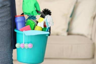 Odasında temizlik malzemesi olan bir hademe.