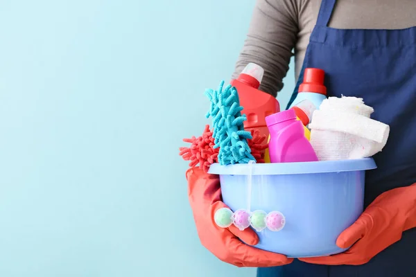 Janitor com conjunto de suprimentos de limpeza em fundo de cor — Fotografia de Stock