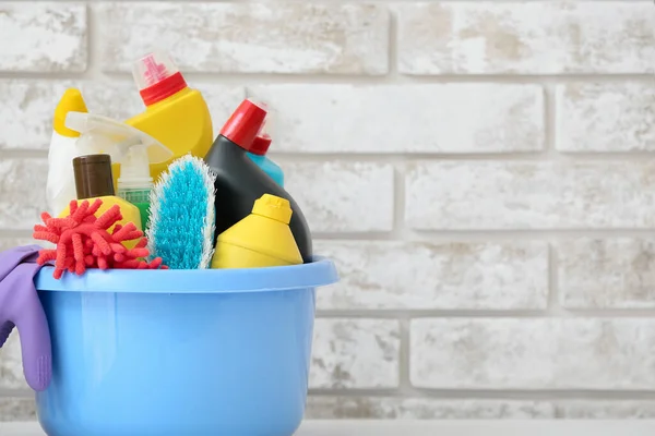 Set of cleaning supplies on brick background